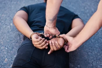 Man laying face down on asphalt with his hands in cuffs behind his back